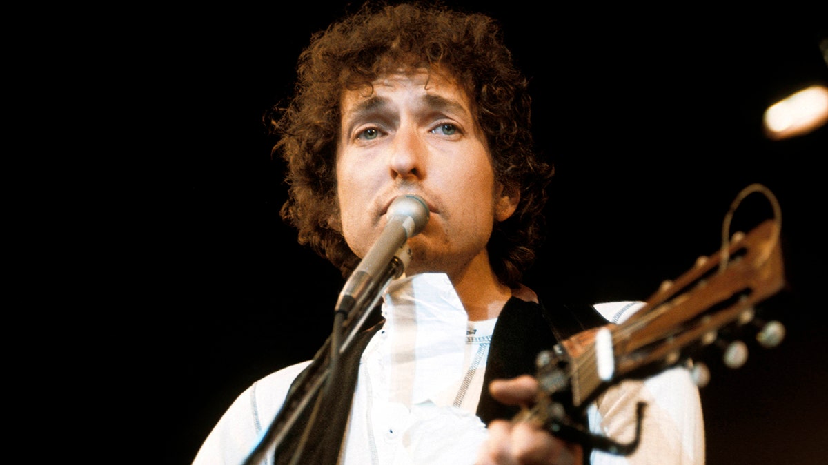 A close-up of Bob Dylan as he sings into a mic