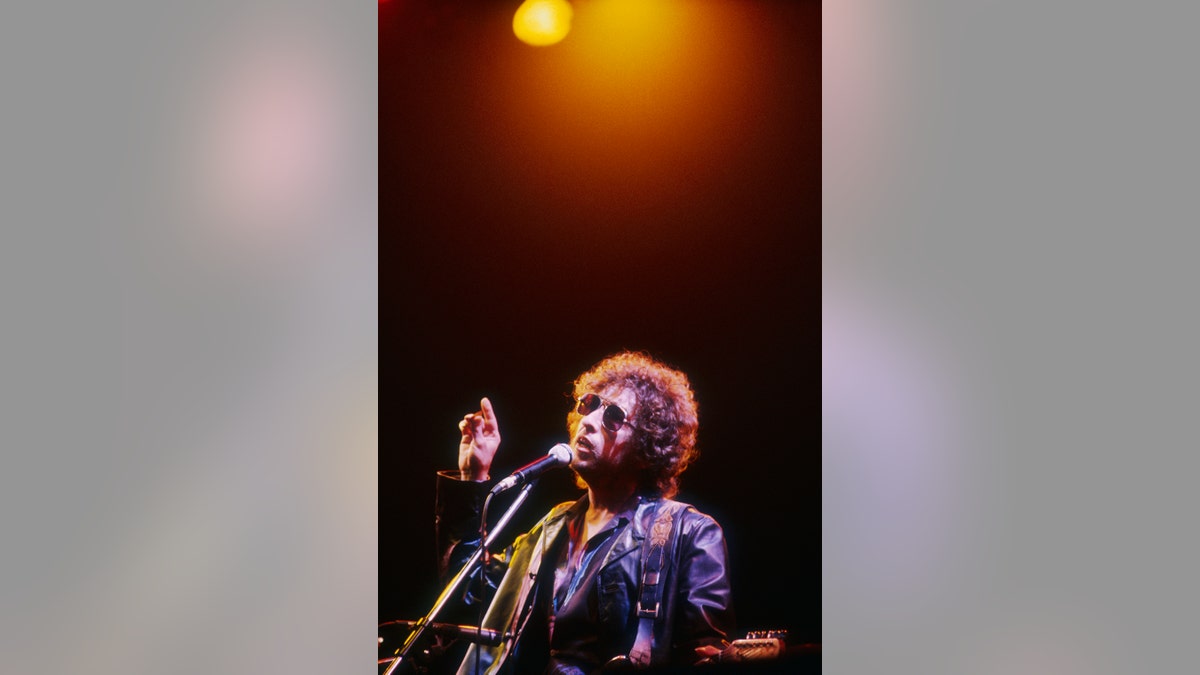 Bob Dylan cantando enquanto uma luz brilha acima de sua cabeça