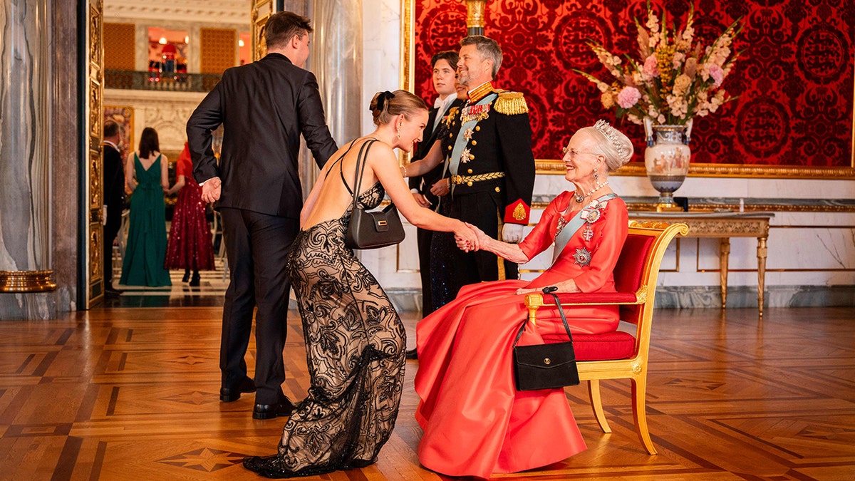 Anne-Sofie Toernsoe Olesen bowing down to the queen in a spaghetti strap gown