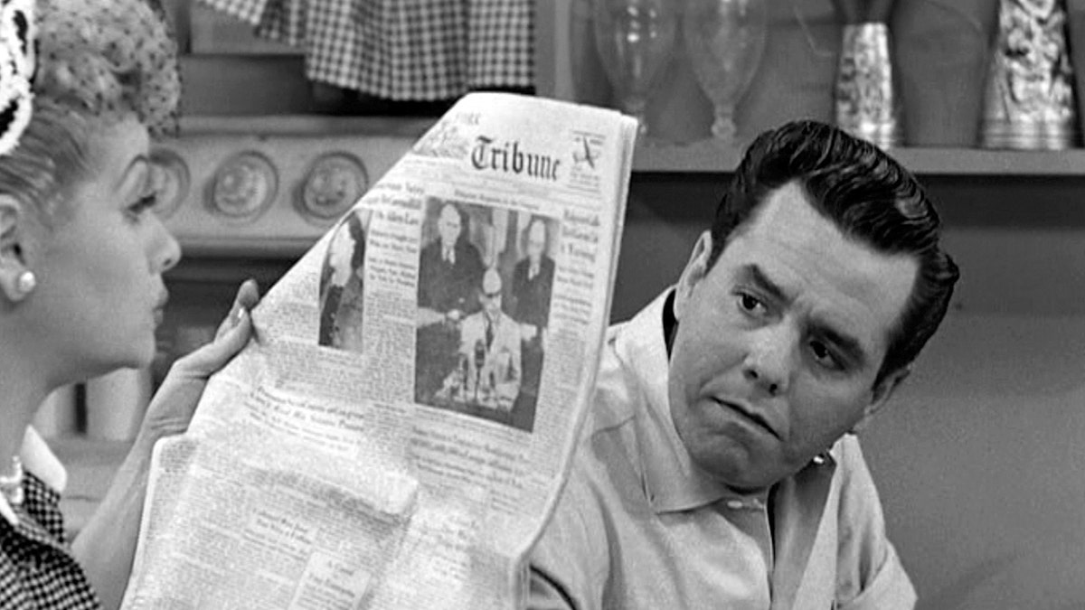 Desi Arnaz looking upset as Lucille Ball ignores him and reads a newspaper