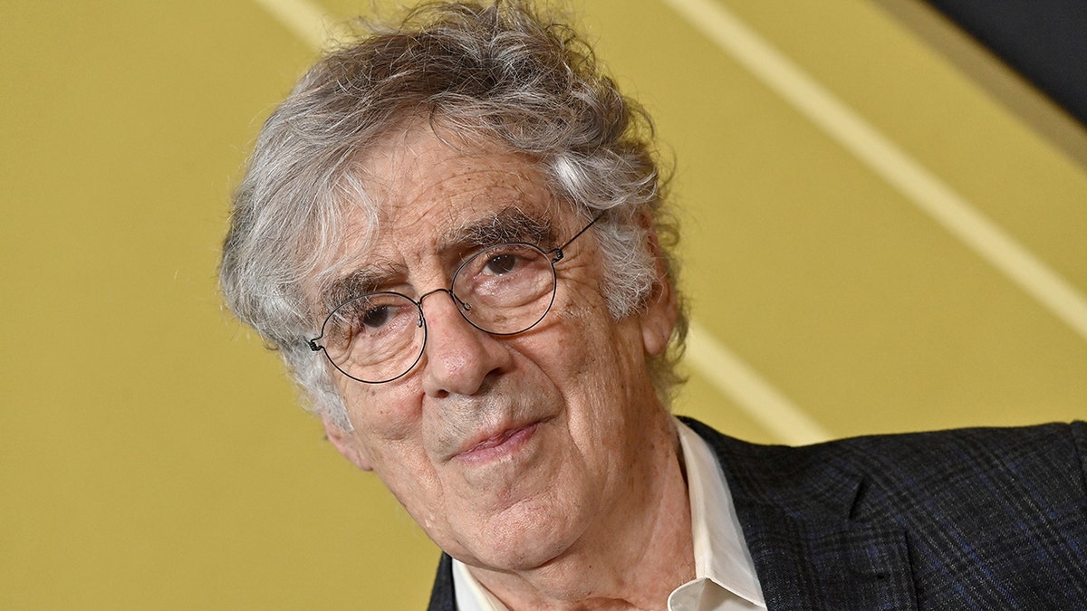 Un primer plano de Elliott Gould con traje y gafas de lectura