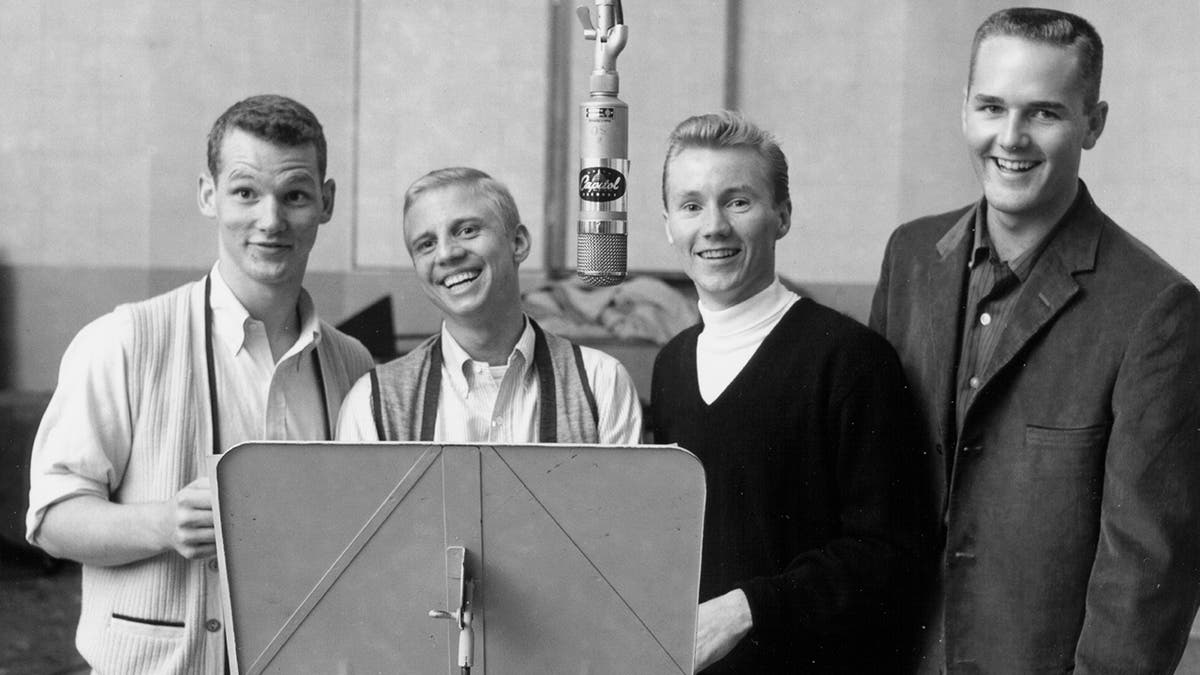 The Four Preps smiling in front of a mic at a studio