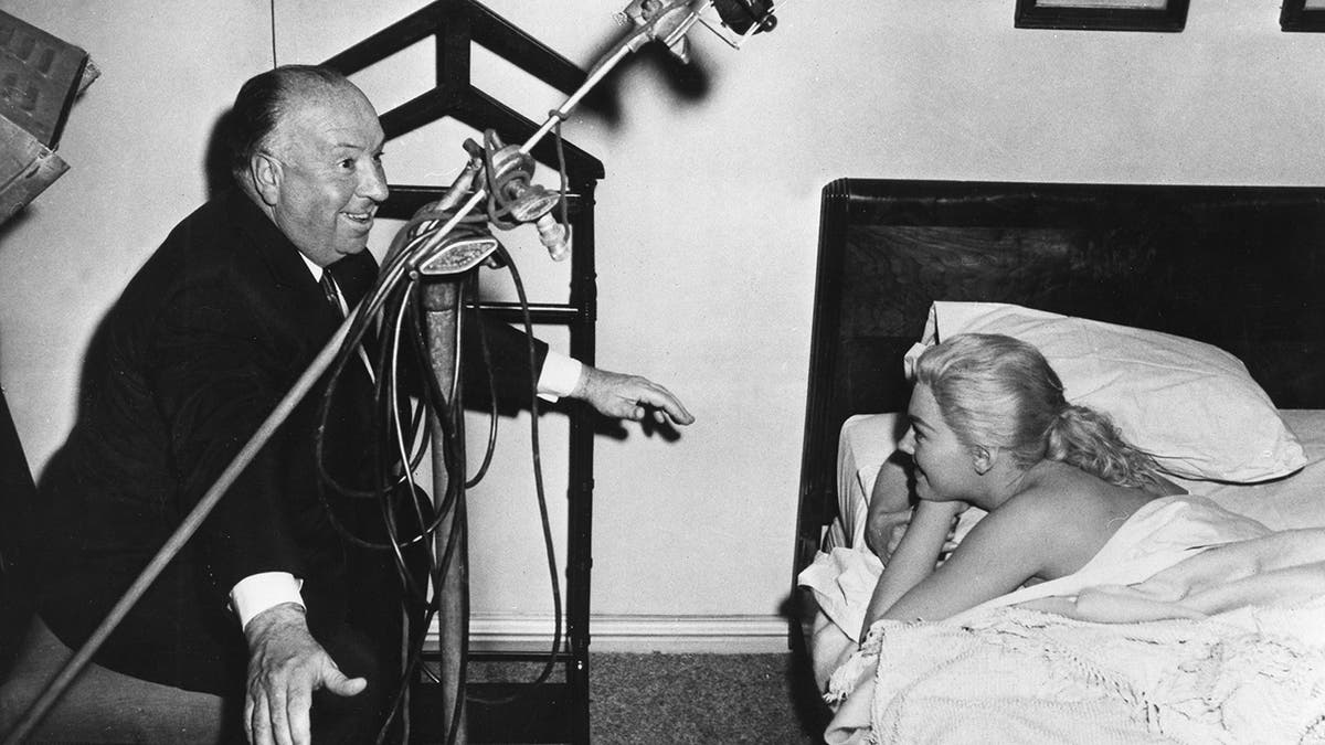 Alfred Hitchcock directing Kim Novak as she lays in bed
