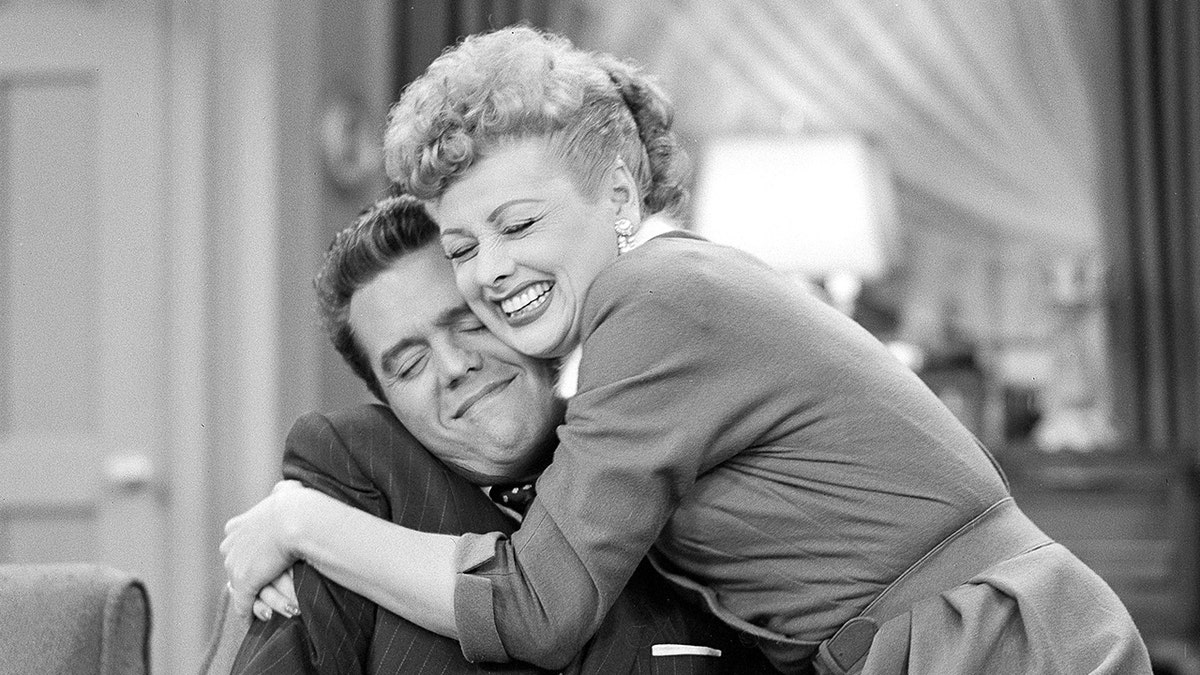 Lucille Ball smiling and embracing Desi Arnaz who is also smiling