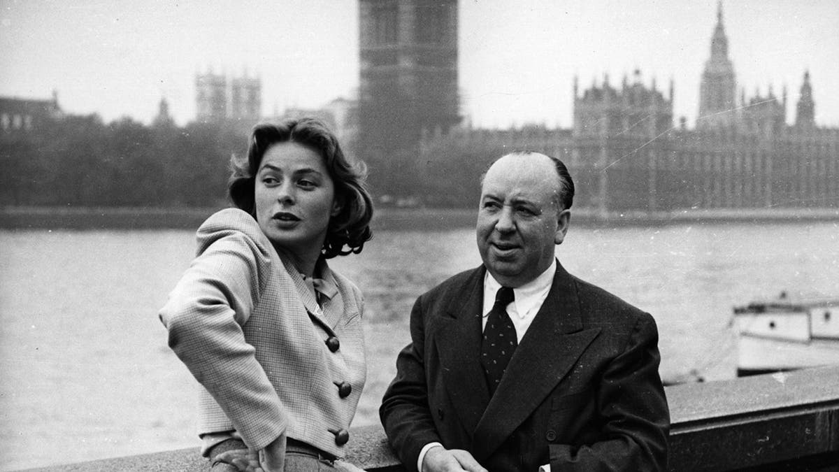 Ingrid Bergman looking away from Alfred Hitchcock while they are in formal wear
