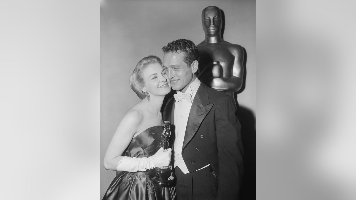 Joanne Woodward smiling and canoodling with Paul Newman as she holds her Oscar award