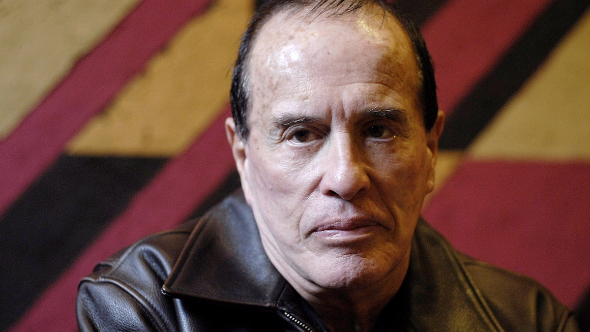 Un primo piano di Kenneth Anger che indossa una giacca di pelle