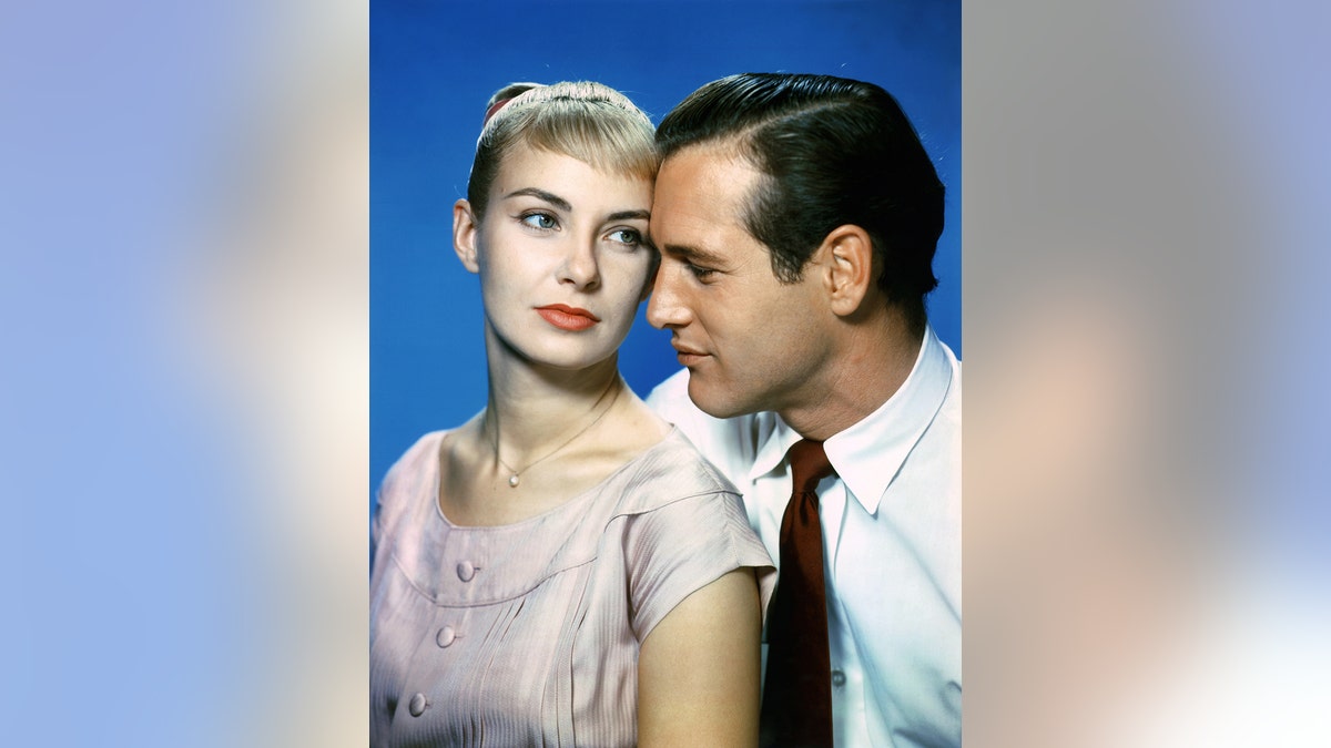 Joanne Woodward wearing a pale pink dress as Paul Newman looks at her