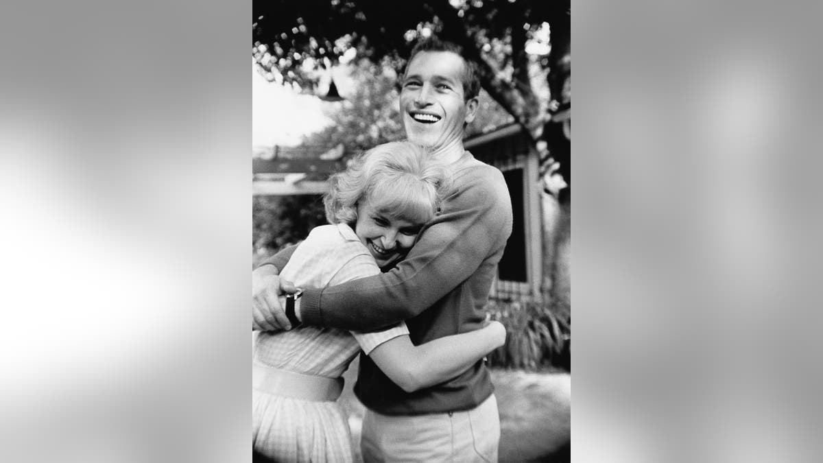 Un Paul Newman sorridente che abbraccia una Joanne Woodward ridente all'aperto