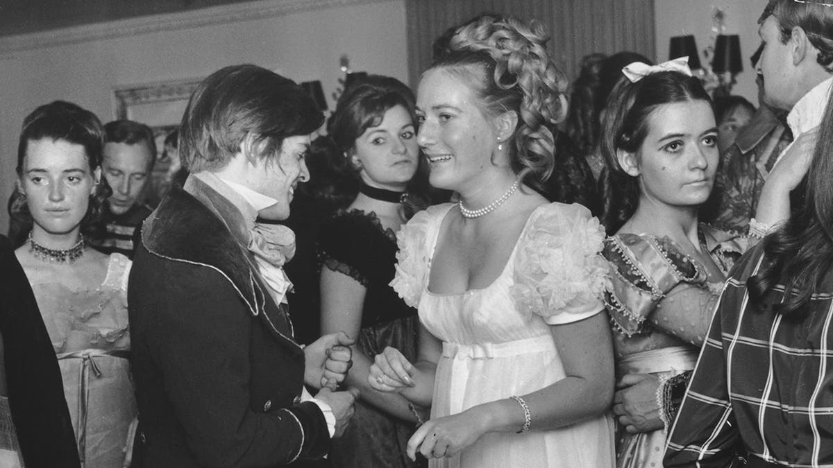A close-up of Princess Olga Romanoff in a white gown surrounded by people