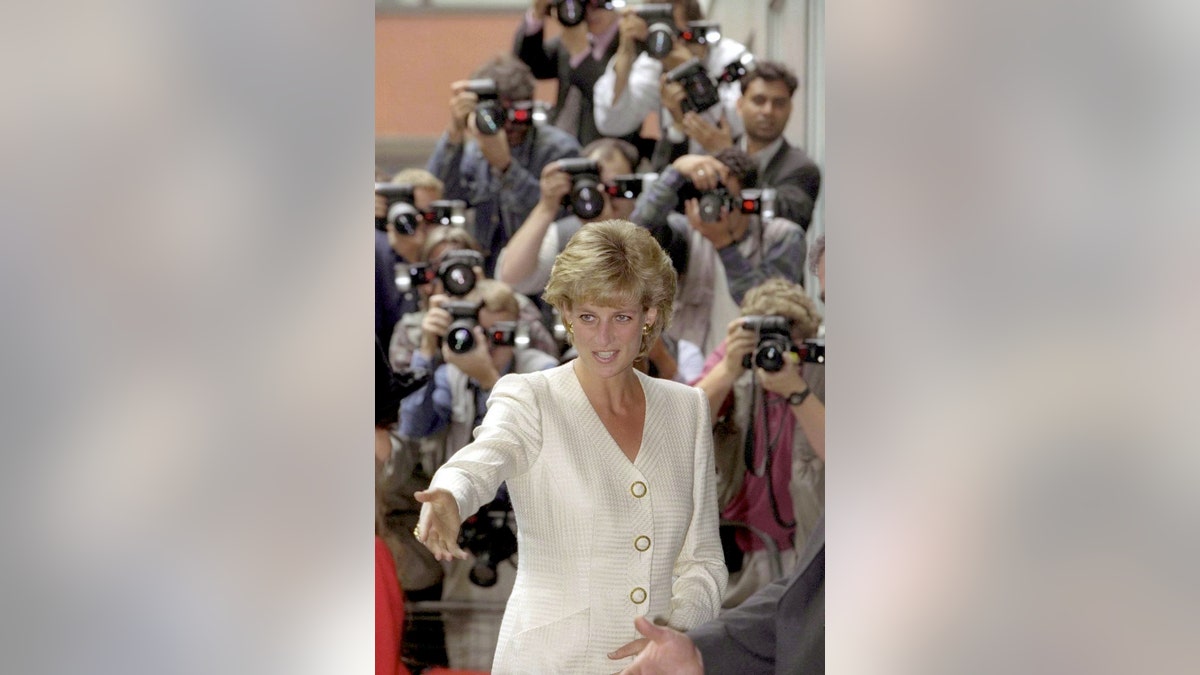 Princess Diana wearing an ivory suit as photographers surround her