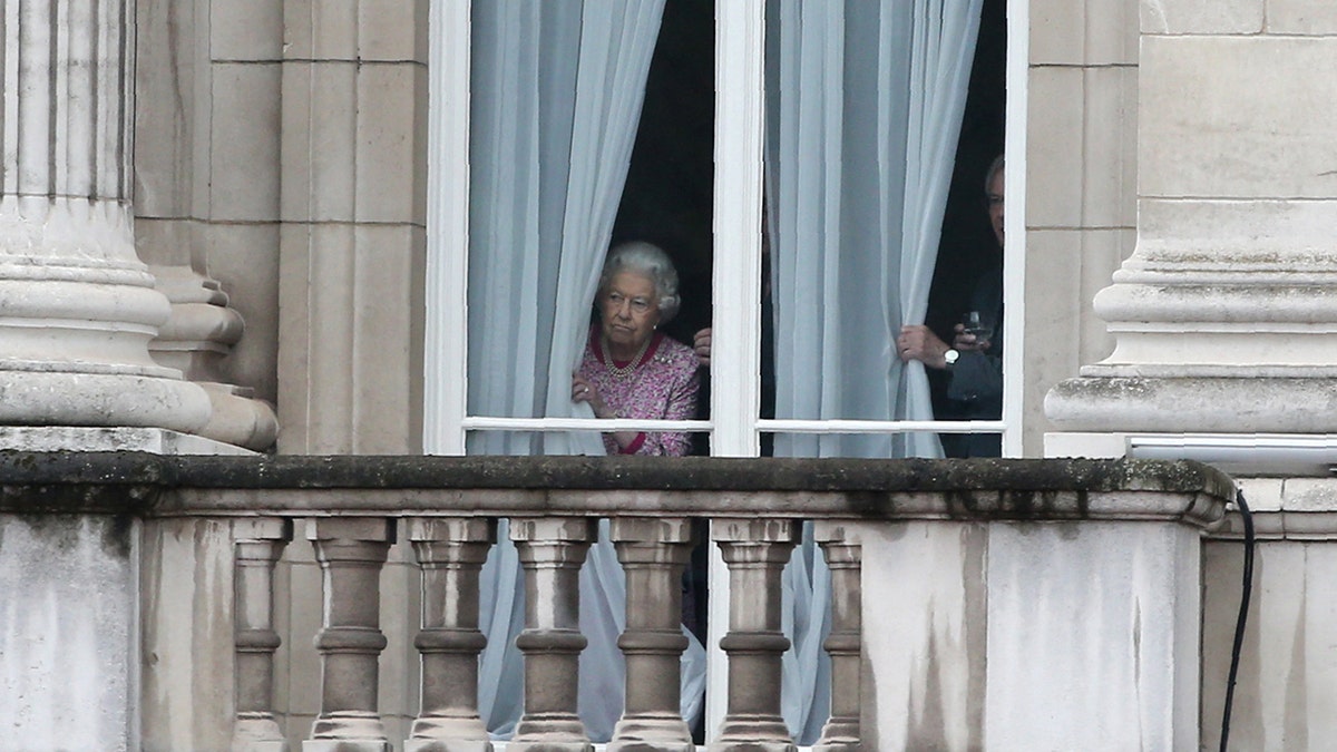 Queen Elizabeth looking out the window from Buckingham Palace