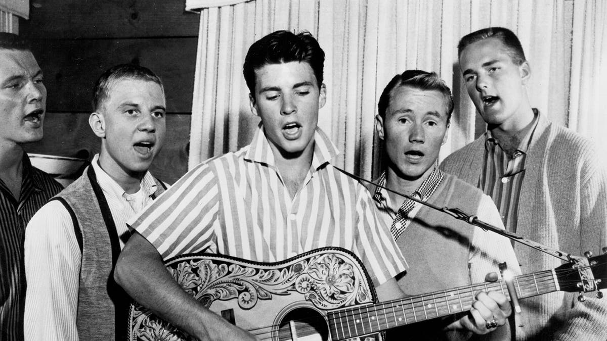 Ricky Nelson performing with the Four Preps as he plays a guitar
