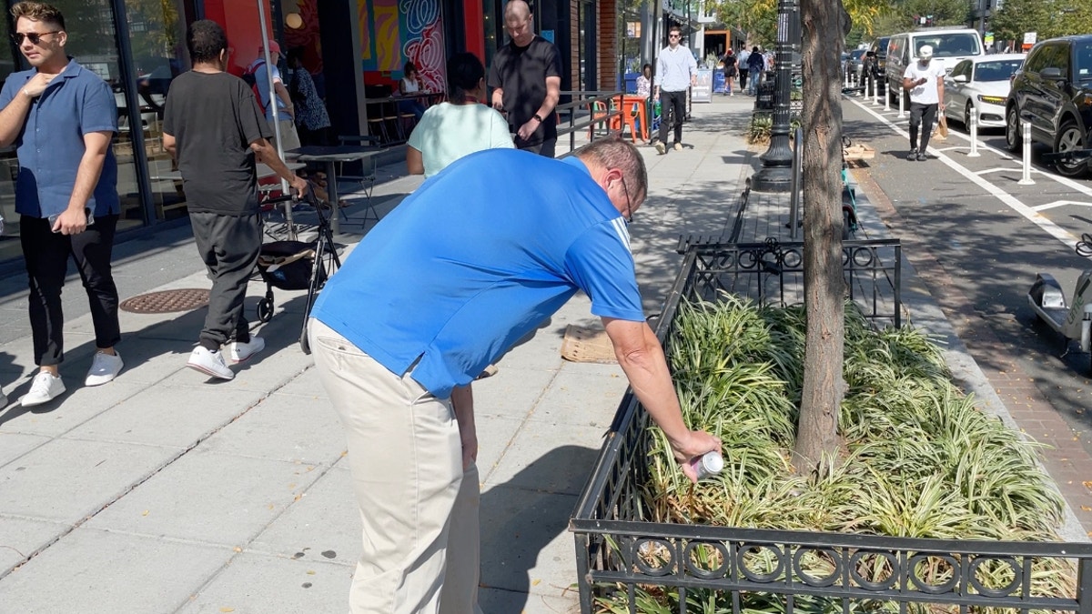 Chad pours his Coke into a planter on the sidewalk