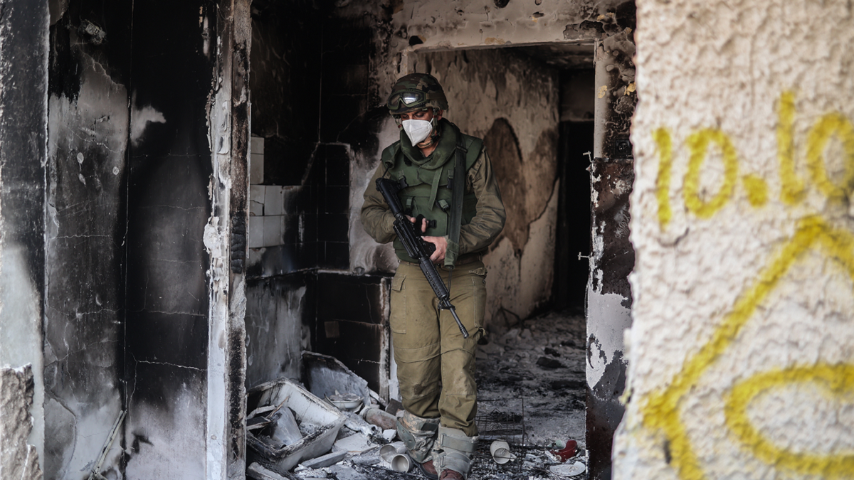 Soldado israelense caminha por casa destruída