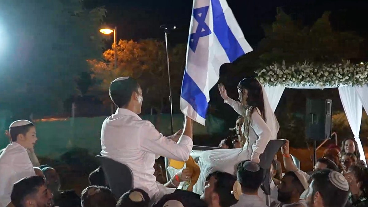 A bride and groom celebrating their wedding with an Israeli flag.