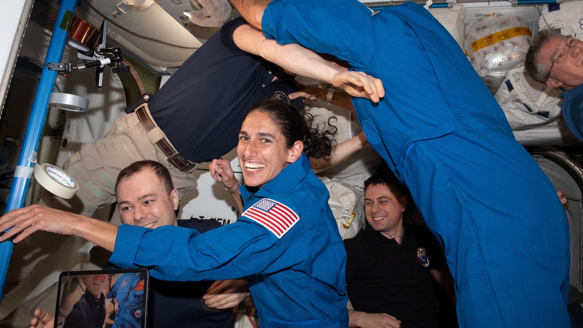 NASA astronaut Jasmine Mogbel surrounded by floating crew members on the ISS