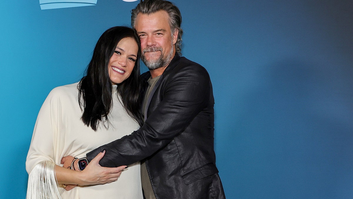 Audra Mari and Josh Duhamel hugging on the red carpet