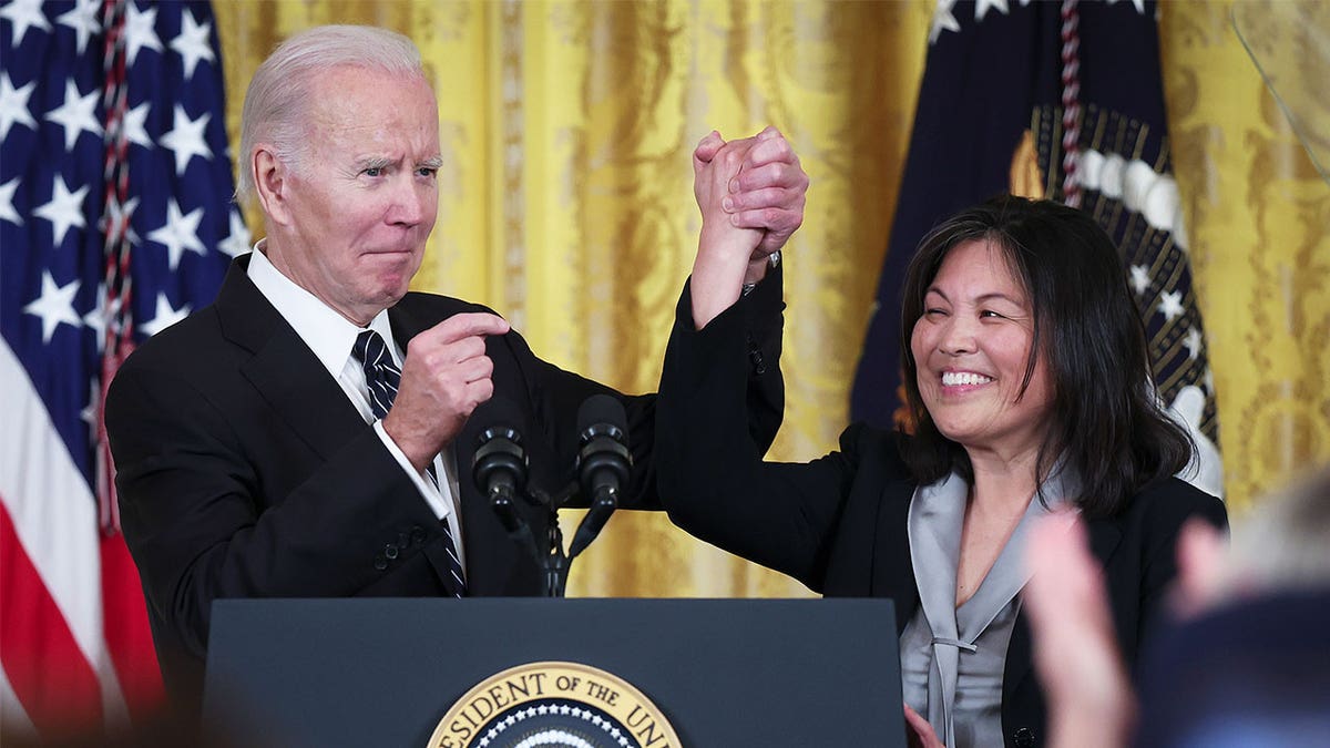 Julie Su, right, with President Joe Biden raising up her hand