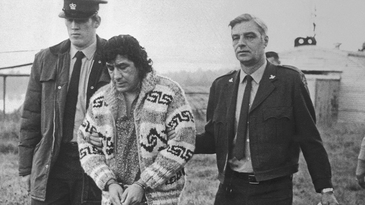 Leonard Peltier, American Indian Movement leader, is led across Okalla prison exercise yard to a waiting helicopter. After a prolonged legal battle, Peltier was ordered deported by Canadian Justice Minister Ron Basford to face charges of murdering two FBI agents.