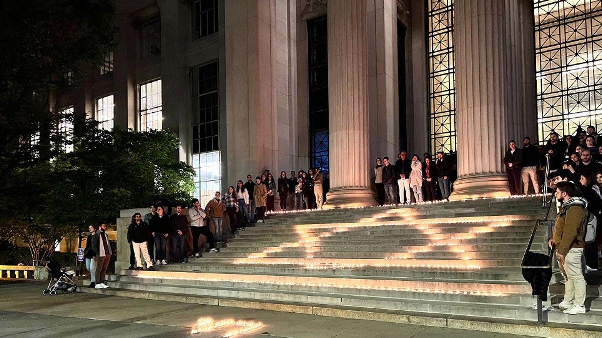 Israel supporters gather around a light portraying the Star of David on building steps at the MIT campus