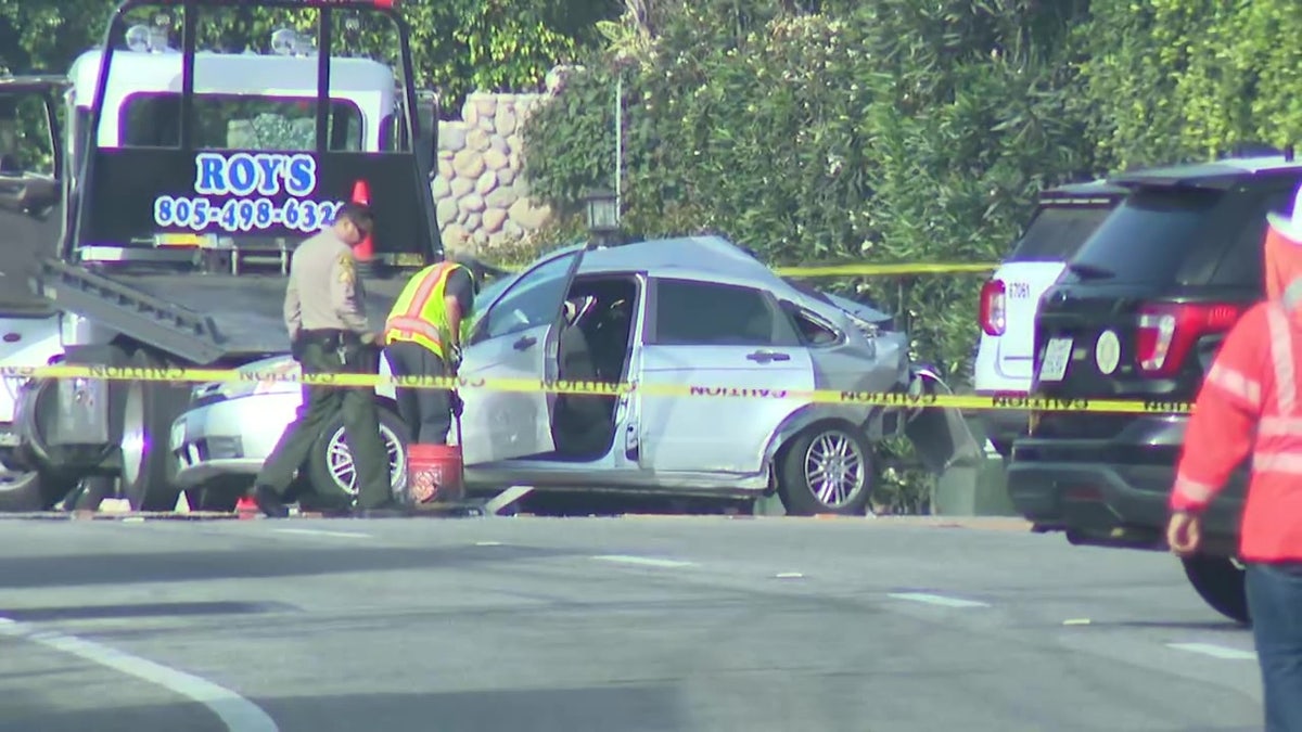 A mangled car is shown behind caution tape.