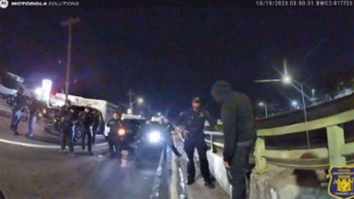 Police officers speaking with a man before he tries to jump off overpass