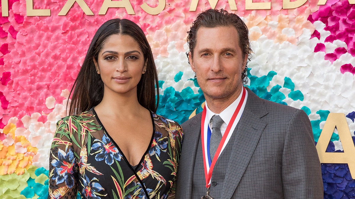 Camila Alves in a patterned dress and Matthew McConaughey in a grey suit with a medal around his neck