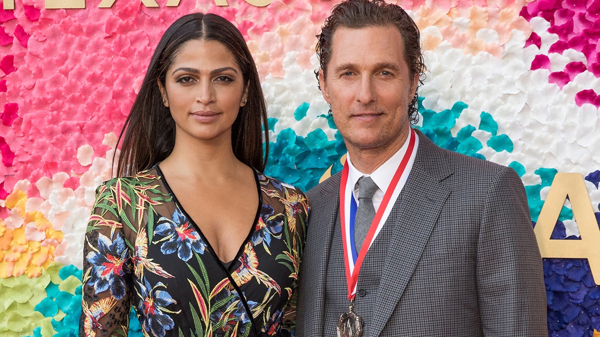 Camila Alves in a patterned dress and Matthew McConaughey in a grey suit with a medal around his neck