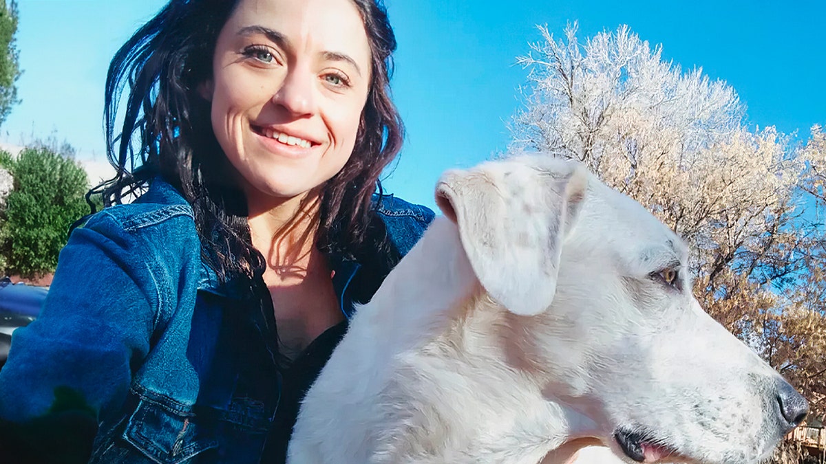 Woman poses with white dog.