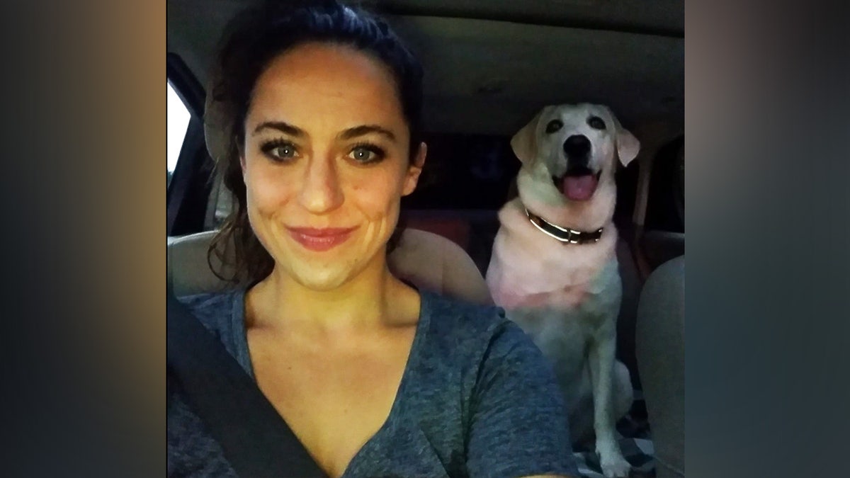 Woman takes selfie with white dog in car.