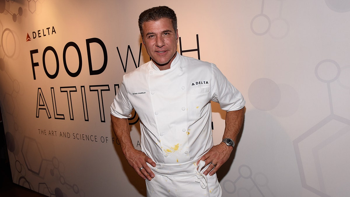 Michael Chiarello con le mani sui fianchi in abito bianco da chef