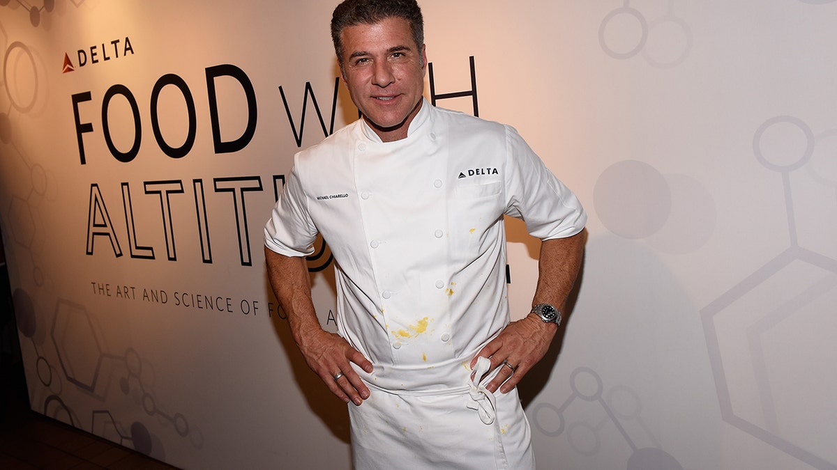 Michael Chiarello con le mani sui fianchi in abito bianco da chef