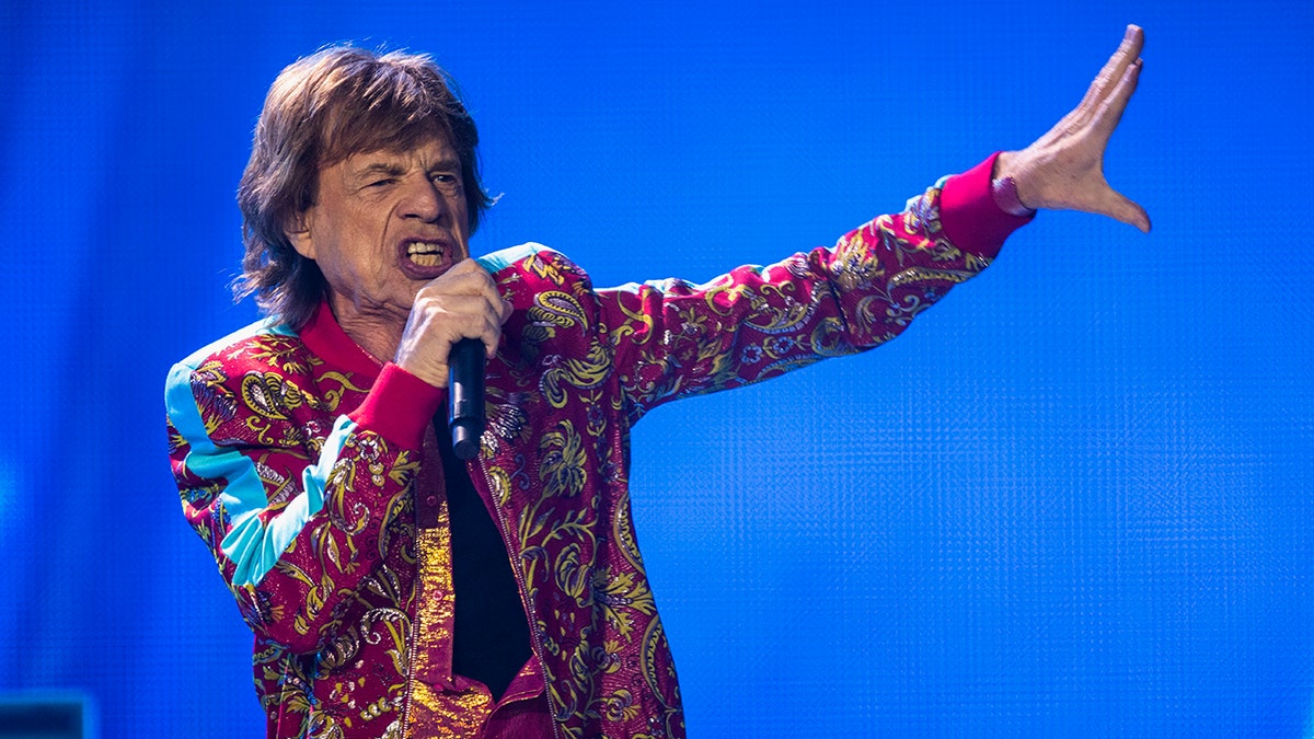Mick Jagger holding a microphone and singing on stage