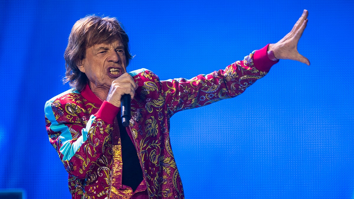 Mick Jagger holding a microphone and singing on stage