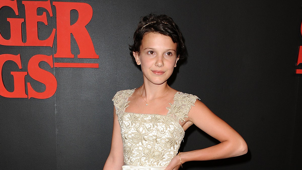 Millie Bobby Brown posing as a 12-year-old on the Stranger Things red carpet