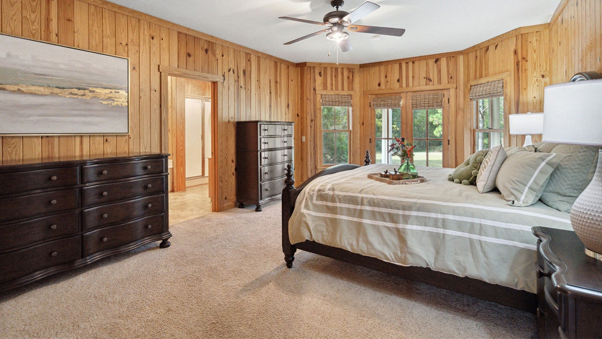 A carpeted bedroom with pine walls.