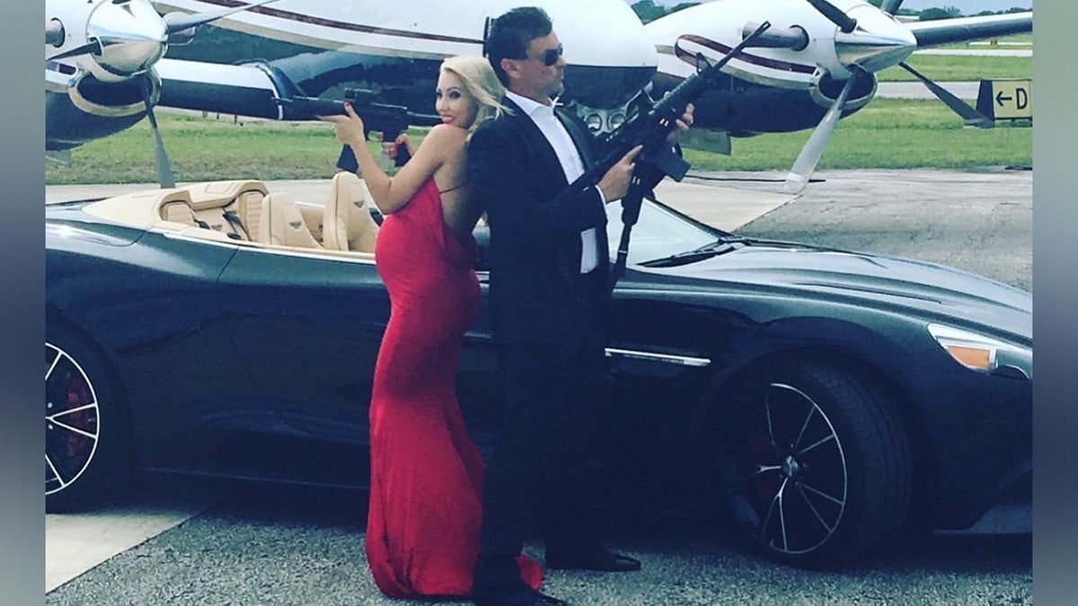 Couple pose like James Bond in front of luxury car.