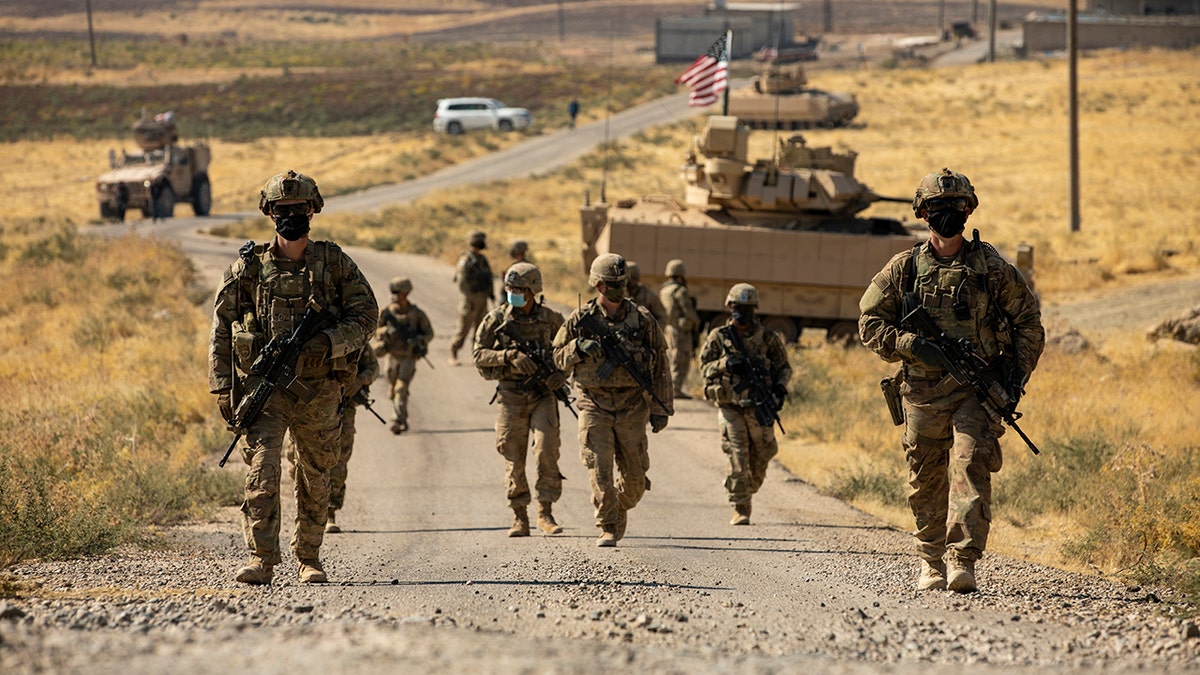 US soldiers march on road in Syria in 2020