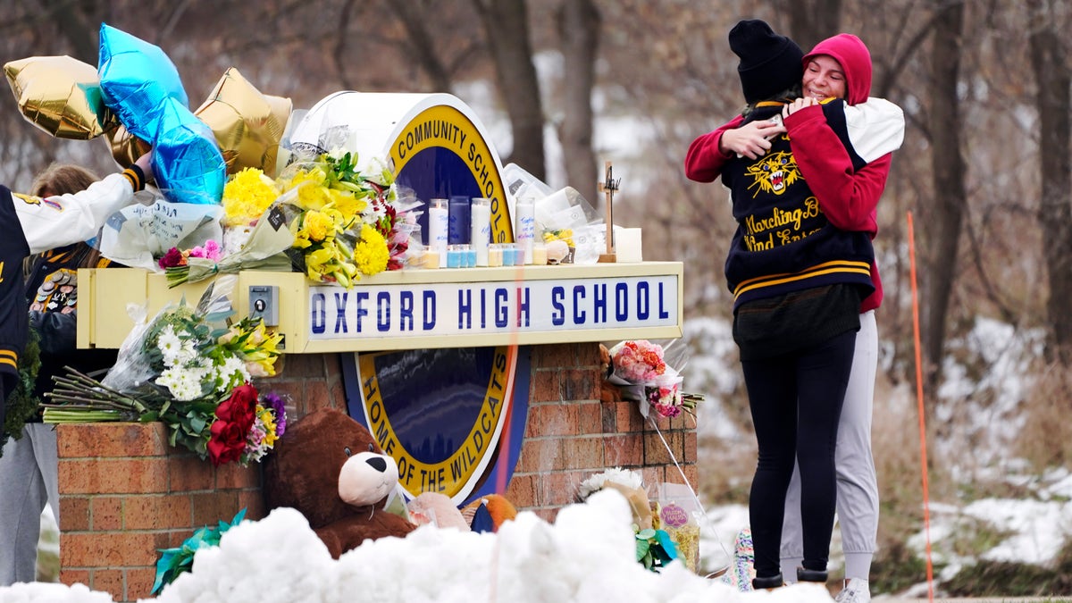 Students hug at a memorial outside Oxford High School