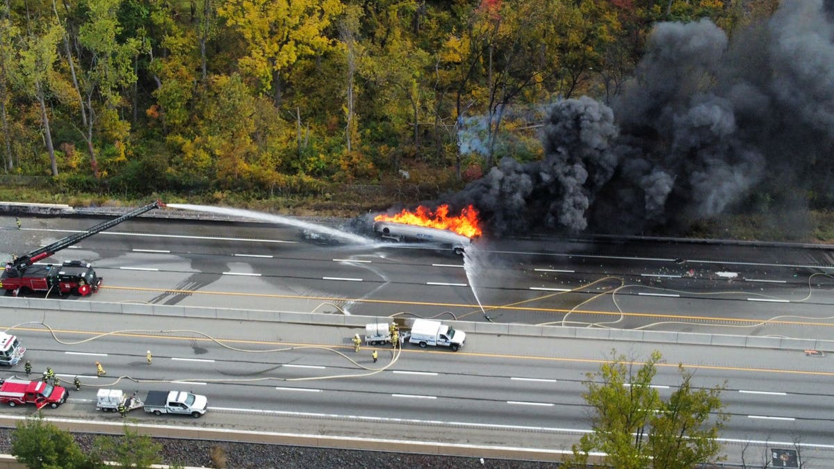 Firefighters hitting a burning tanker with water and foam