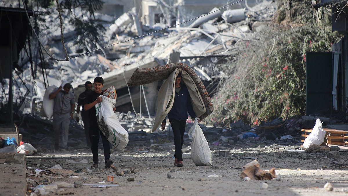 Palestinians walk away from damaged buildings