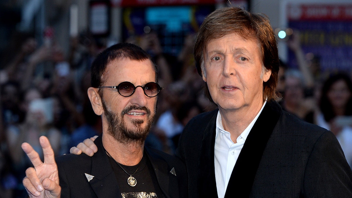 Ringo Starr flashing a peace sign while posing with Paul McCartney