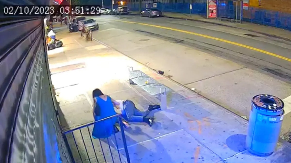 Woman kneels beside injured man on street.