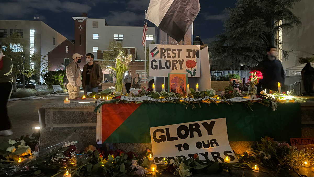 Signs and candles at the base of a clock on the George Washington University campus