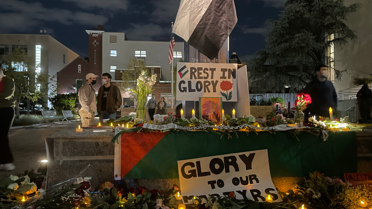 Signs and candles at the base of a clock on the George Washington University campus