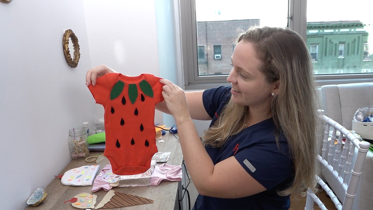 woman holding strawberry jumpsuit