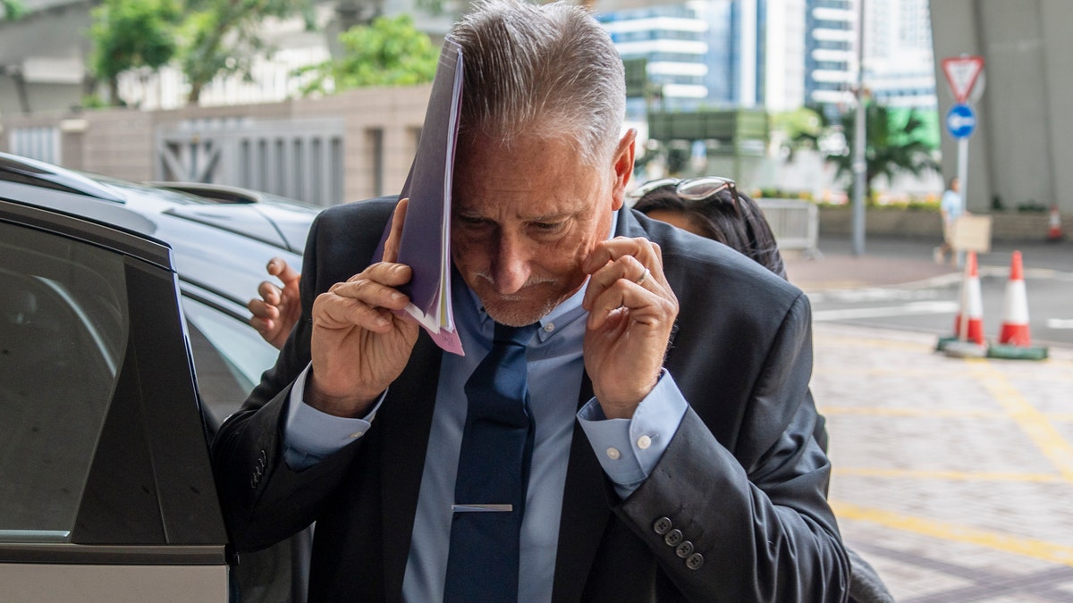 Sen. Jeff Wilson covers his face as he arrives at court in Hong Kong