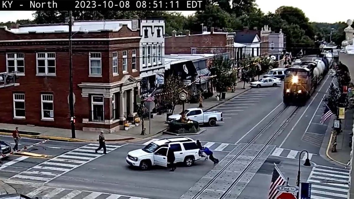 Good Samaritans rush to the scene to push the stalled SUV off of the tracks.