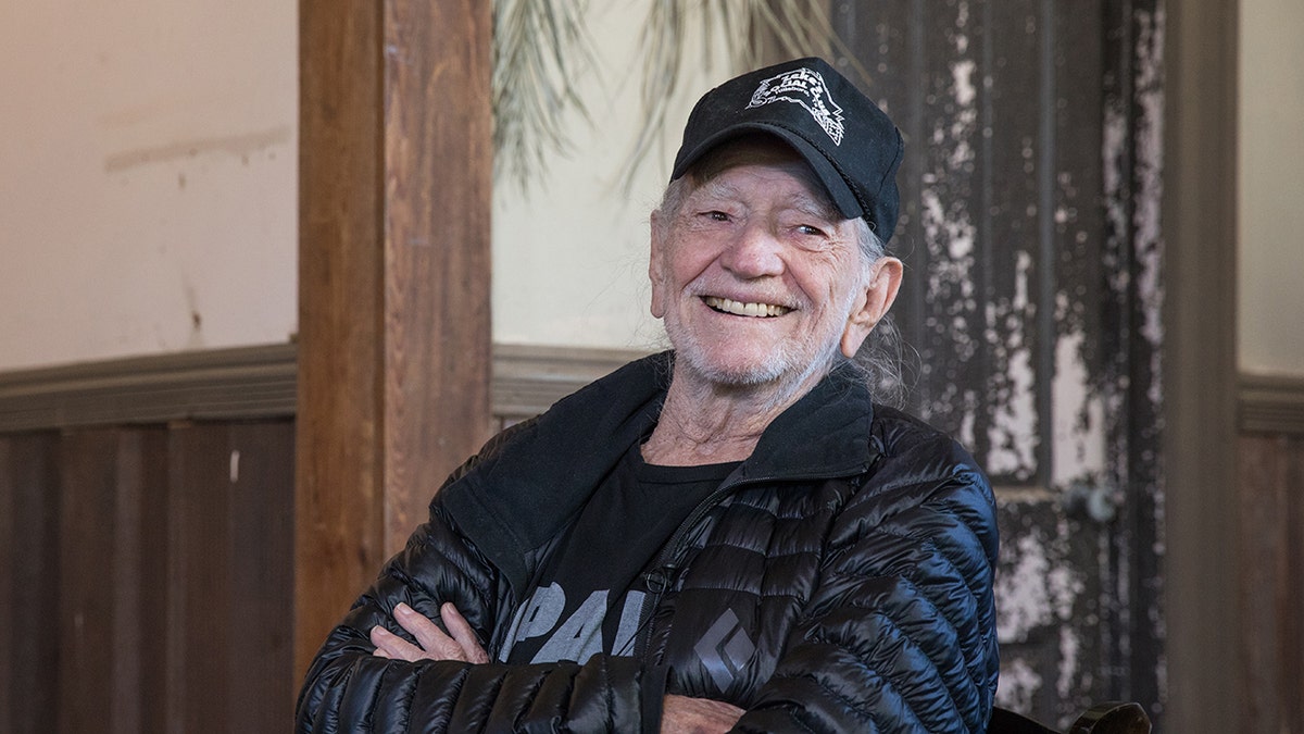 Willie Nelson sorride con le braccia incrociate sul petto